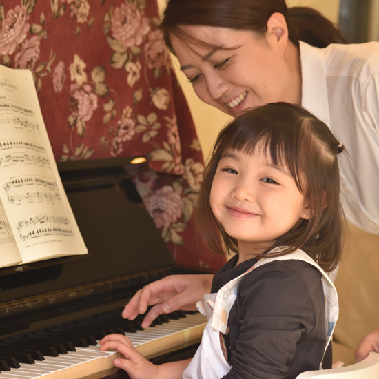 ピアノを弾きながら微笑む女の子の写真